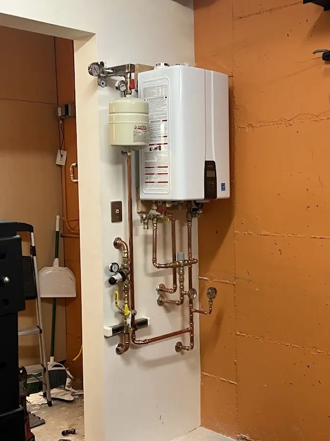 Plumbing technician inspecting water heater connections in Grain Valley